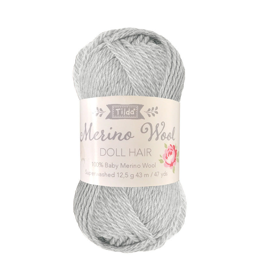 A skein of Tilda Basics Doll Hair yarn in fog gray color, packaged with a label displaying the product information.
Photo by Tildafabrics.com [image_link]