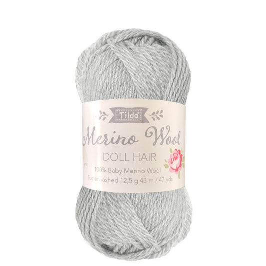 A skein of Tilda Basics Doll Hair yarn in fog gray color, packaged with a label displaying the product information.
Photo by Tildafabrics.com [image_link]