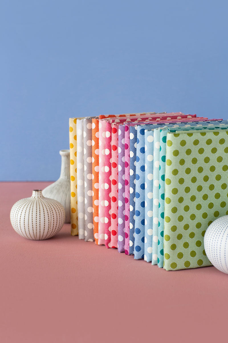 Colorful polka dot notebooks arranged on a pink surface with a blue background.
Photo by Tildafabrics.com [additional_image_link]