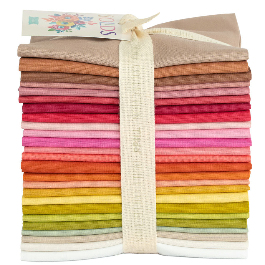A bundle of solid colored fat quarter fabric pieces from Tilda Basics collection, tied together with a fabric band.
Photo by Tildafabrics.com [image_link]