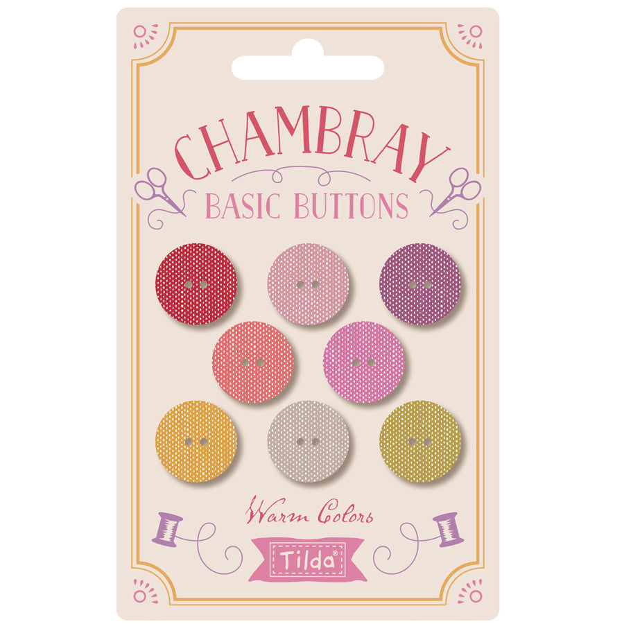 A package of Chambray Basic Buttons in warm colors by Tilda. The card packaging features eight round buttons in shades of red, pink, purple, yellow, and beige, displayed on a cream-colored card with decorative pink and gold borders.
Photo by Tildafabrics.com [image_link]