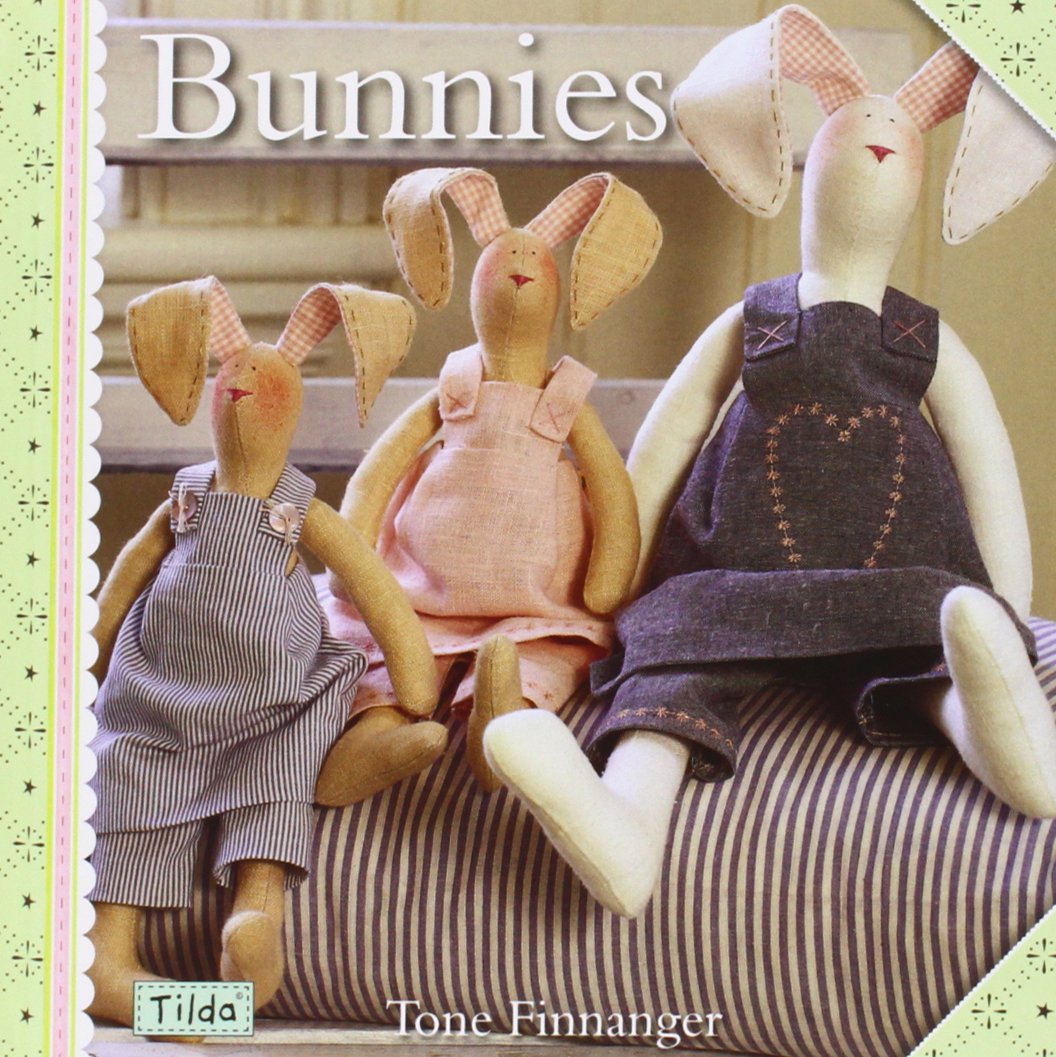 Front cover of a sewing pattern or craft book titled 'Bunnies' by Tone Finnanger, showing three handmade bunny dolls in different outfits sitting on a striped cushion.
Photo by Tildafabrics.com [additional_image_link]