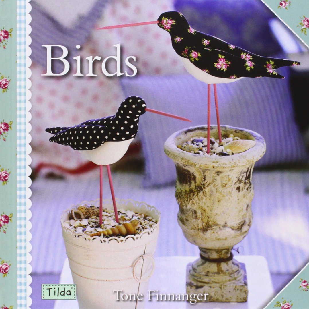 A book cover titled "Birds" by Tone Finnanger, featuring two decorative bird figurines perched on old-style plant pots against a softly blurred indoor background. The cover has a floral border and the brand/name "Tilda" appears in a small label near the bottom left.
Photo by Tildafabrics.com [additional_image_link]