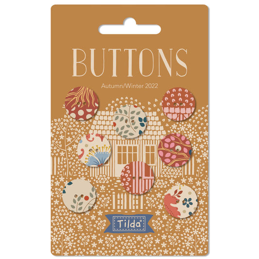 Buttons for crafting, featuring a set of autumn and winter themed round buttons displayed on their original brown cardboard backing card. The buttons feature various patterns like stripes, polka dots, and florals in muted earthy tones.
Photo by Tildafabrics.com [image_link]