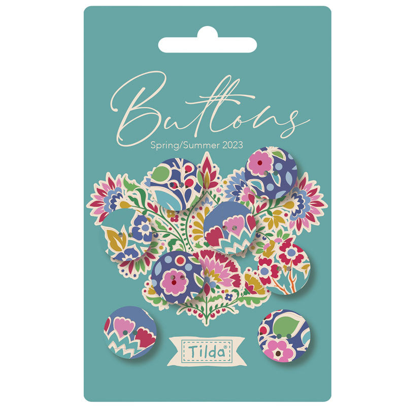 A retail package of decorative buttons labeled 'Buttons Spring/Summer 2023' by Tilda. The package contains multiple round floral and patterned buttons in pink, blue, yellow, green, and purple tones, displayed on a teal backing card.
Photo by Tildafabrics.com [image_link]