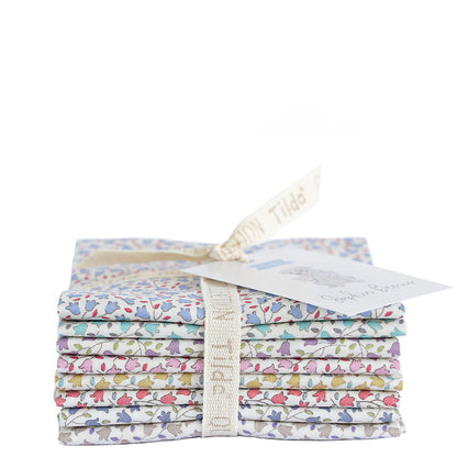 A stack of folded patterned fabric pieces tied with a cream ribbon and tag, photographed on a plain white background.
Photo by Tildafabrics.com [additional_image_link]