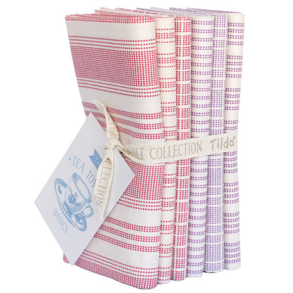 A set of six folded fabrics with gingham and striped patterns in pink, red, purple, and white, tied together with a ribbon and paper tag.
Photo by Tildafabrics.com [additional_image_link]