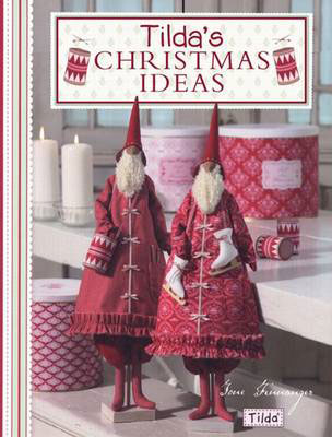 A book cover titled 'Tilda's Christmas Ideas' featuring two festive red Christmas gnome figures in patterned coats and pointed hats, standing beside candles and patterned containers in a styled indoor scene.
Photo by Tildafabrics.com [image_link]
