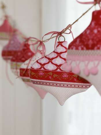 Decorative red and pink ornaments with gold patterns hanging against a white background
Photo by Tildafabrics.com [additional_image_link]