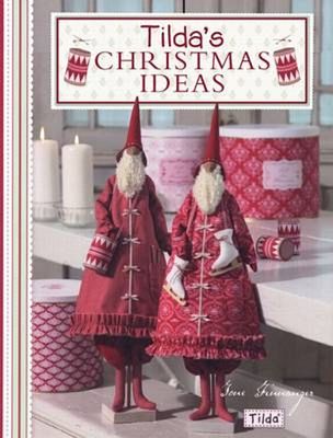 A book cover titled 'Tilda's Christmas Ideas' featuring two festive red Christmas gnome figures in patterned coats and pointed hats, standing beside candles and patterned containers in a styled indoor scene.
Photo by Tildafabrics.com [additional_image_link]