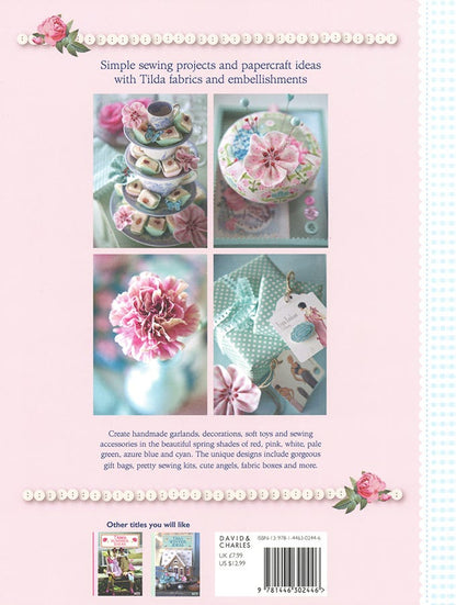 Back cover of a sewing pattern book titled 'Simple sewing projects and papercraft ideas with Tilda fabrics and embellishments' by David Charles. The cover has a light pink background with a central grid of four photos showing decorated cakes, flowers, and handmade crafts.
Photo by Tildafabrics.com [additional_image_link]