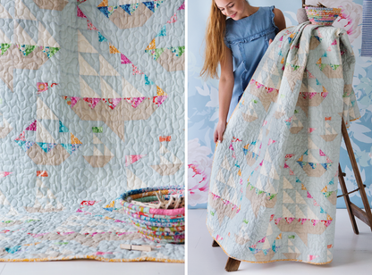 A quilted throw blanket with a patchwork design of light blue, beige, and multicolor floral/bunting motifs, shown both as a close-up detail and being held up by a woman in a blue dress.
Photo by Tildafabrics.com [additional_image_link]