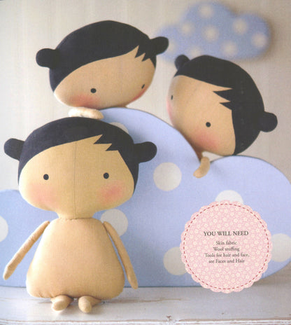 Three handmade fabric doll heads with black hair and pale skin tones, arranged on a light blue polka-dot backdrop with a pink circular text overlay reading 'YOU WILL NEED'.
Photo by Tildafabrics.com [additional_image_link]
