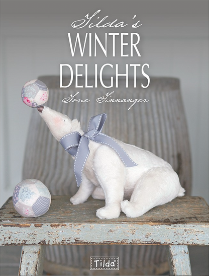 Front cover of Tilda's Winter Delights by Tone Finnanger. There is a polar bear  sitting on a wood stool balancing a ball on it's nose and a larger ball at it's feet.
Photo by Tildafabrics.com [image_link]