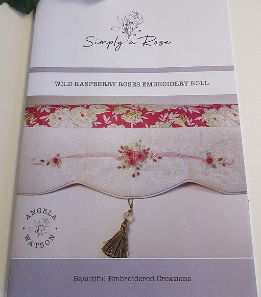 An embroidery roll cover for 'Wild Raspberry Roses' by Simply a Rose, featuring a sample of embroidered fabric with a scalloped border, floral details, and a tassel.
Photo by Angela Watson [image_link]